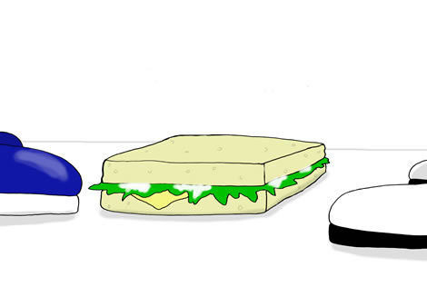 A delicious-looking sandwich on the ground between the opposing feet of two men