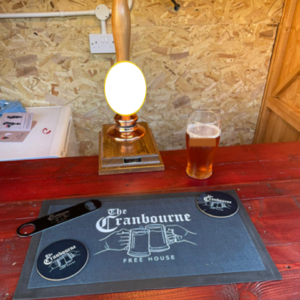 Logo on a bar towel, beer mats and bottle opener all laid out on the bar